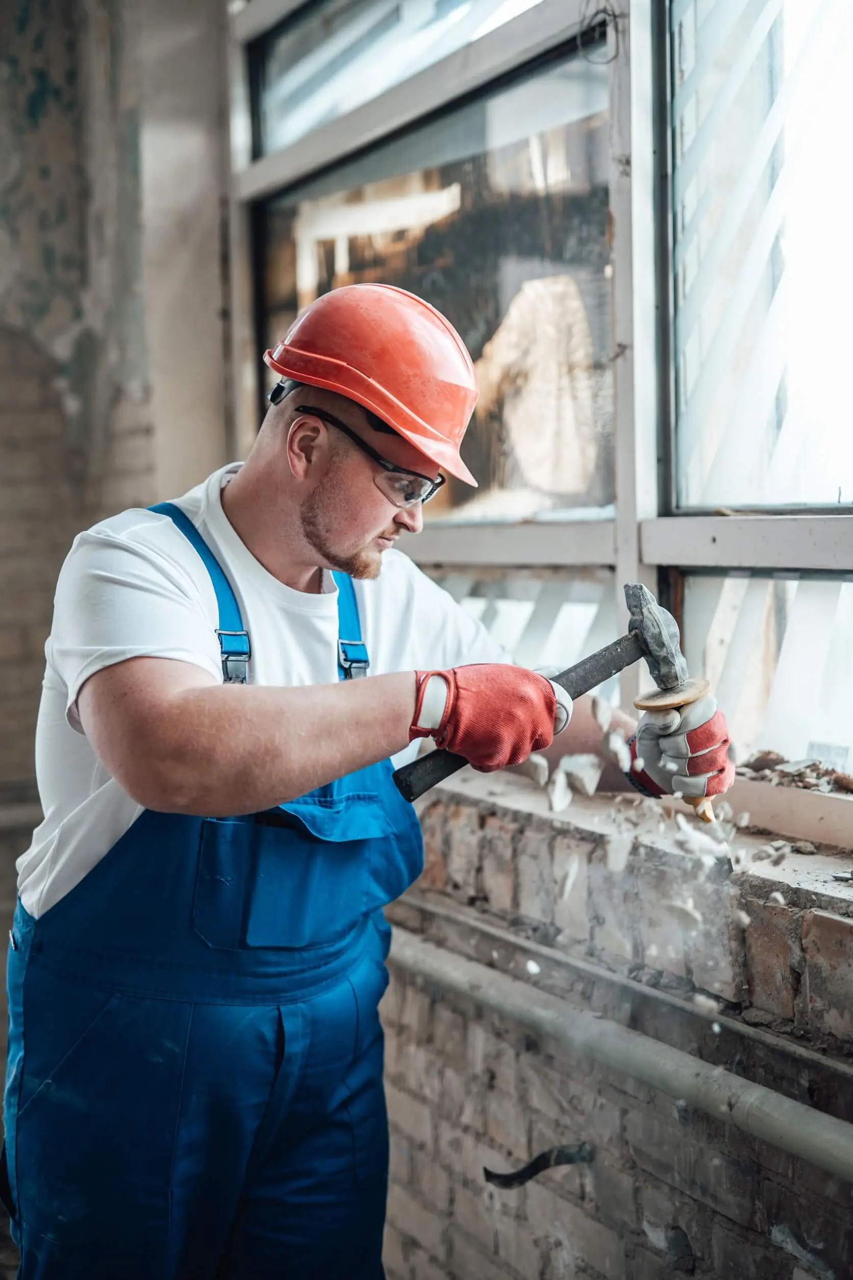 Construction worker chipping brick wall