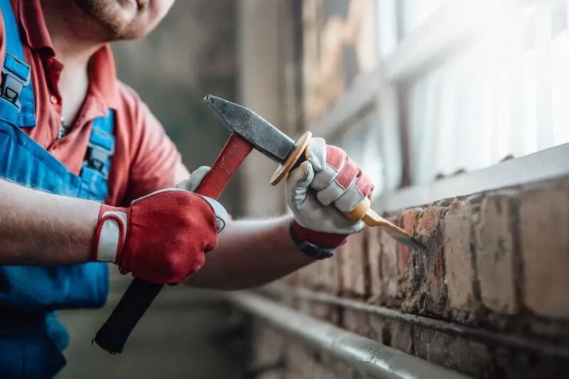 Construction worker repairs brick wall