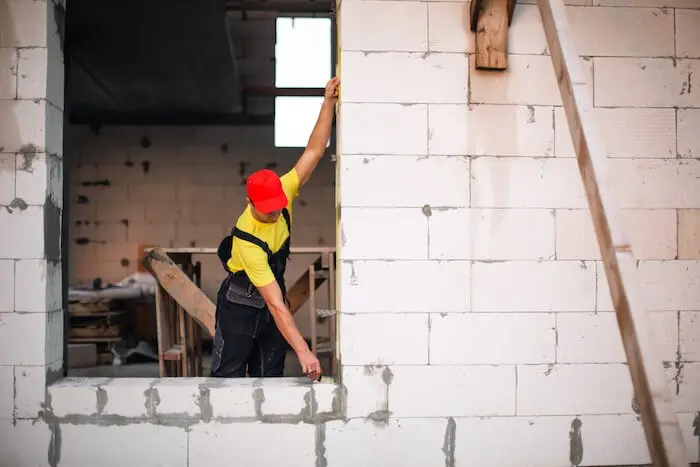 Construction worker inspecting brick wall