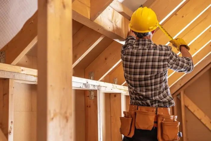 Construction worker measuring wooden framework