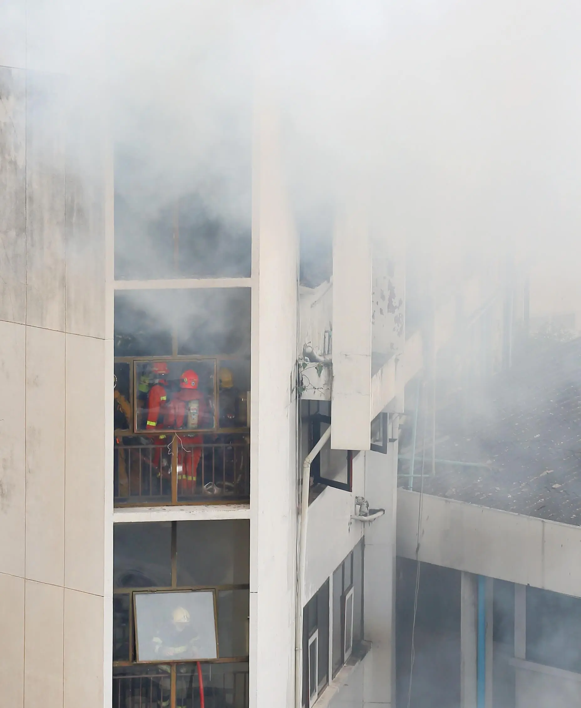 Firefighters extinguishing building fire smoke