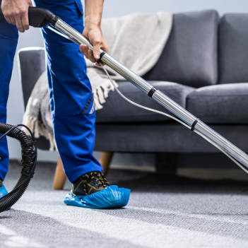 A person cleaning a carpet with a professional water vacuumn machine in a living room