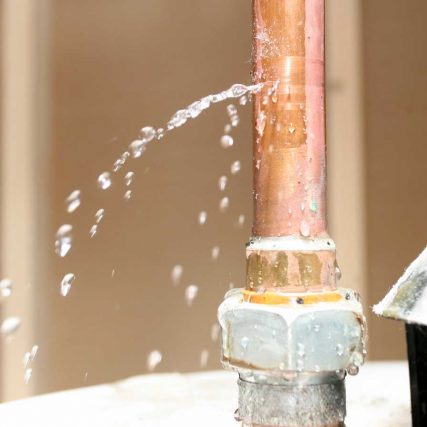 Water leaking from a copper pipe with visible spray